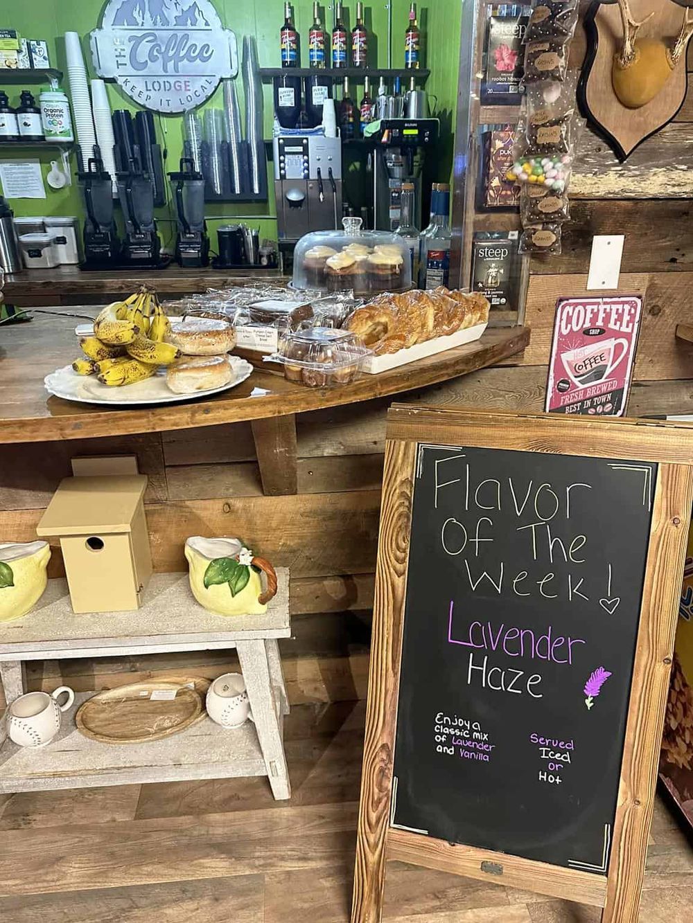 Banana bread and baked goods display at cozy coffee shop, inviting customers to enjoy lavender haze flavor of the week.