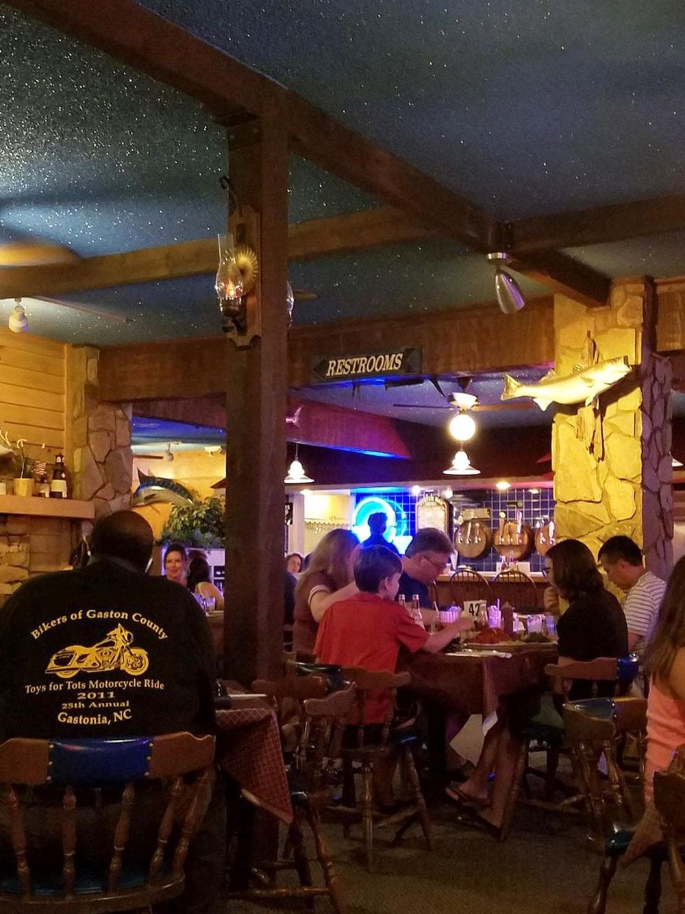 Cozy restaurant interior with group dining, rustic decor, and nautical fish accents, perfect for family meals and casual outings.