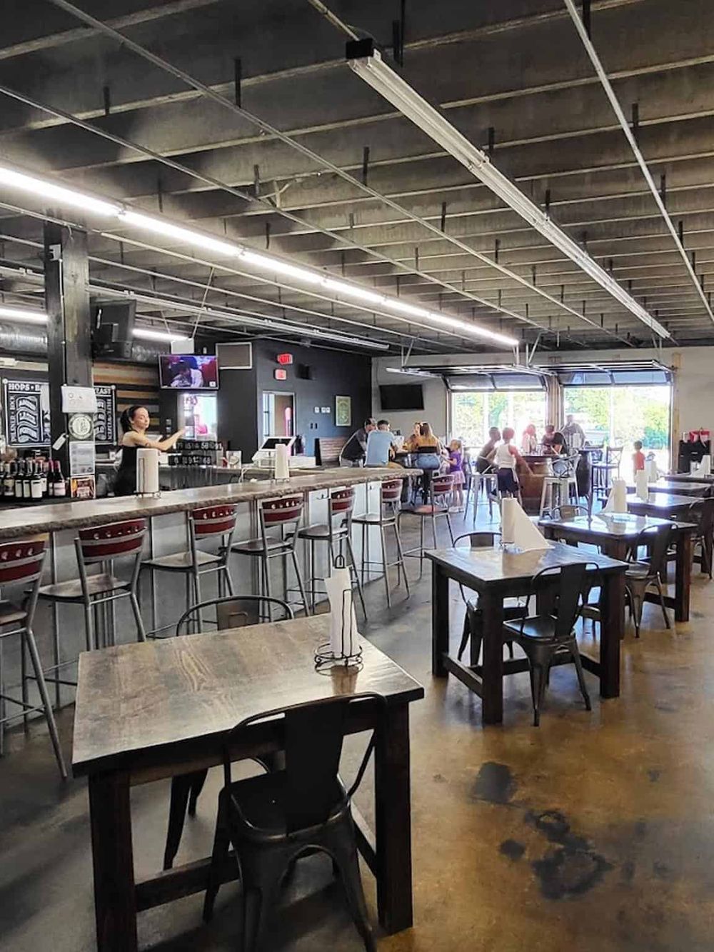 Bright modern restaurant interior with bar seating, customers dining, and a lively casual atmosphere.