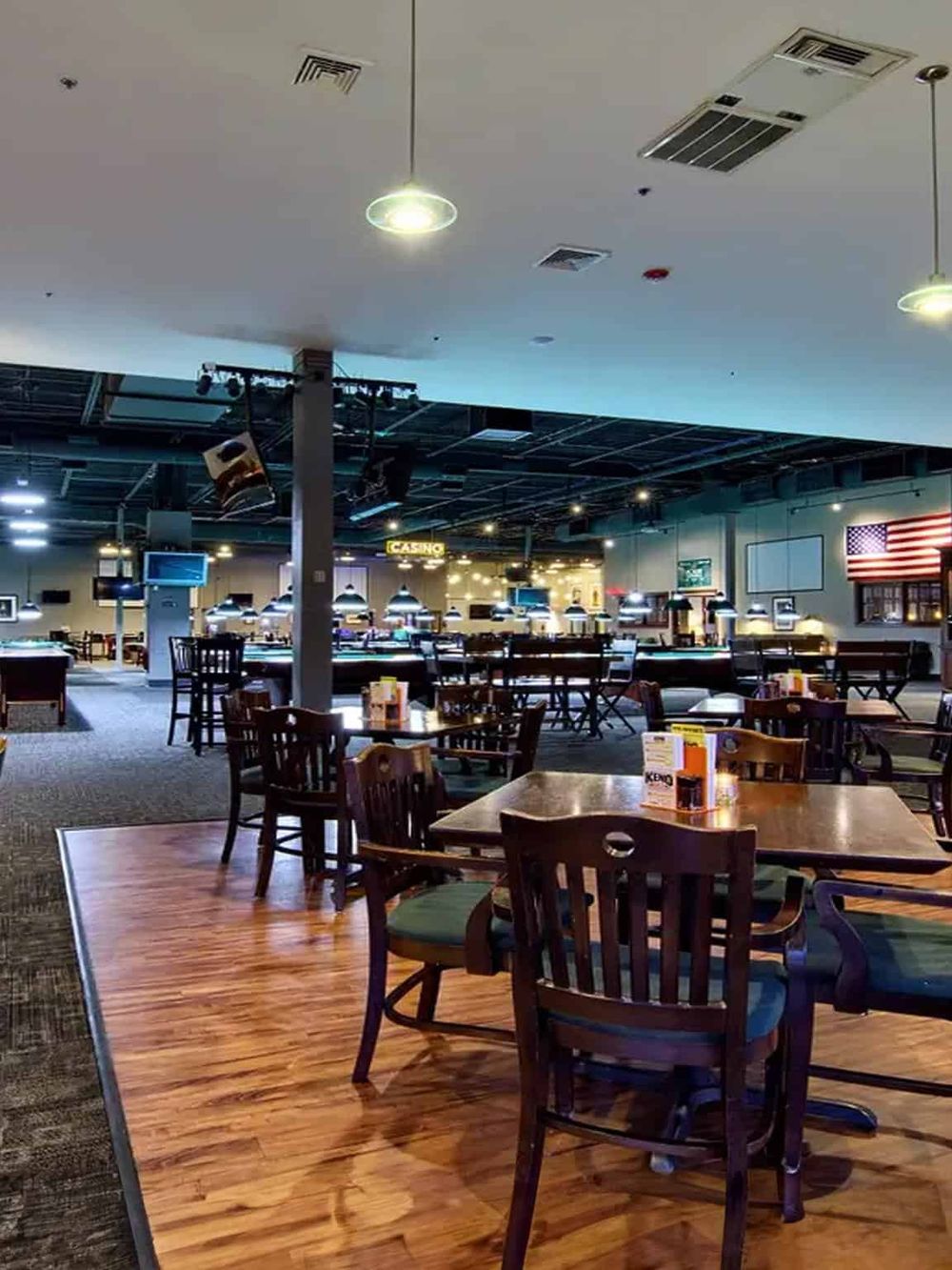 Brightly lit American restaurant interior with pool tables, TV screens, and patriotic decor.