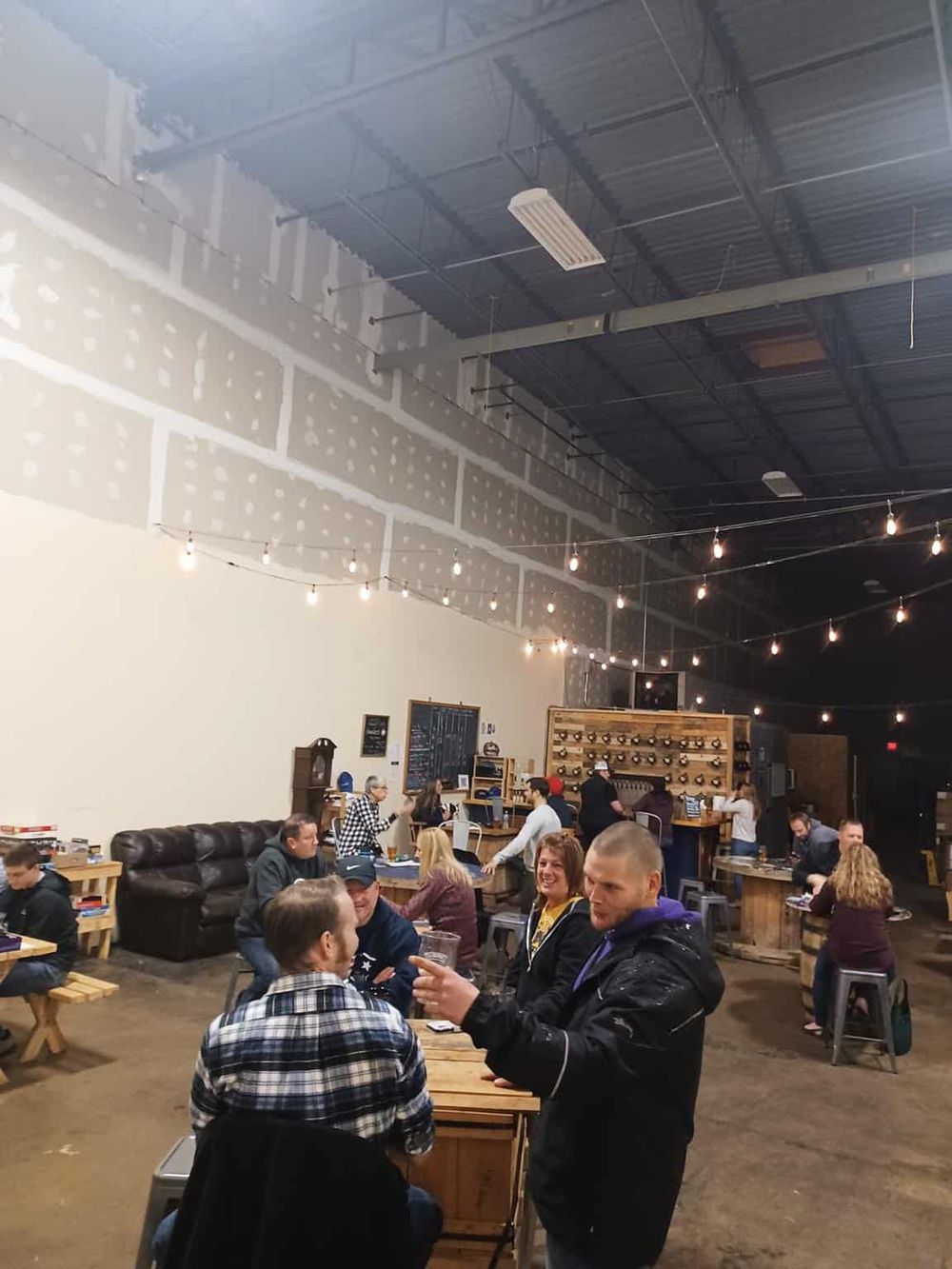 Cozy brewery interior with people enjoying drinks, string lights, and rustic decor at QuestForDirections brewery.