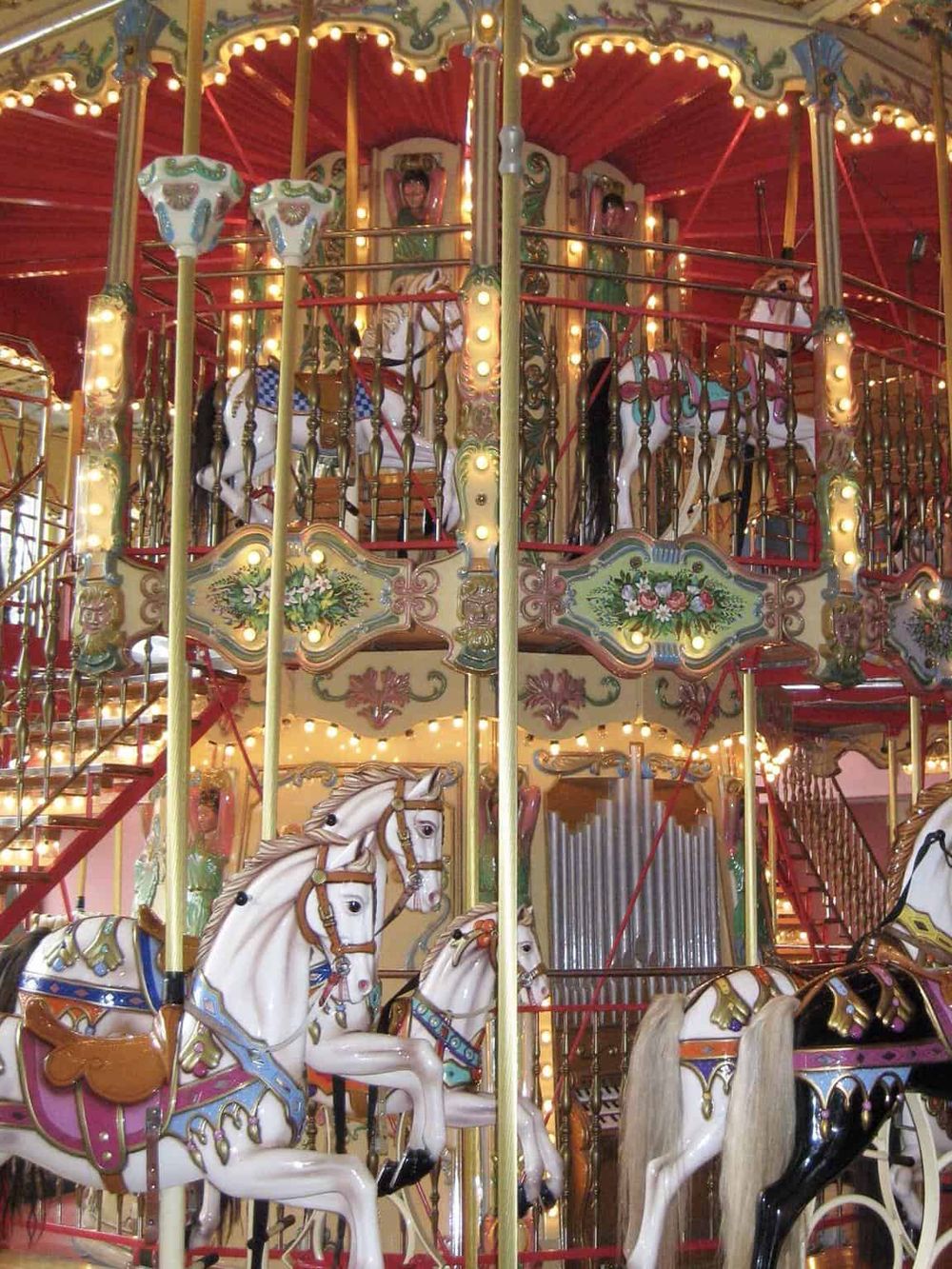 Colorful vintage carousel with white horses and ornate decorations.