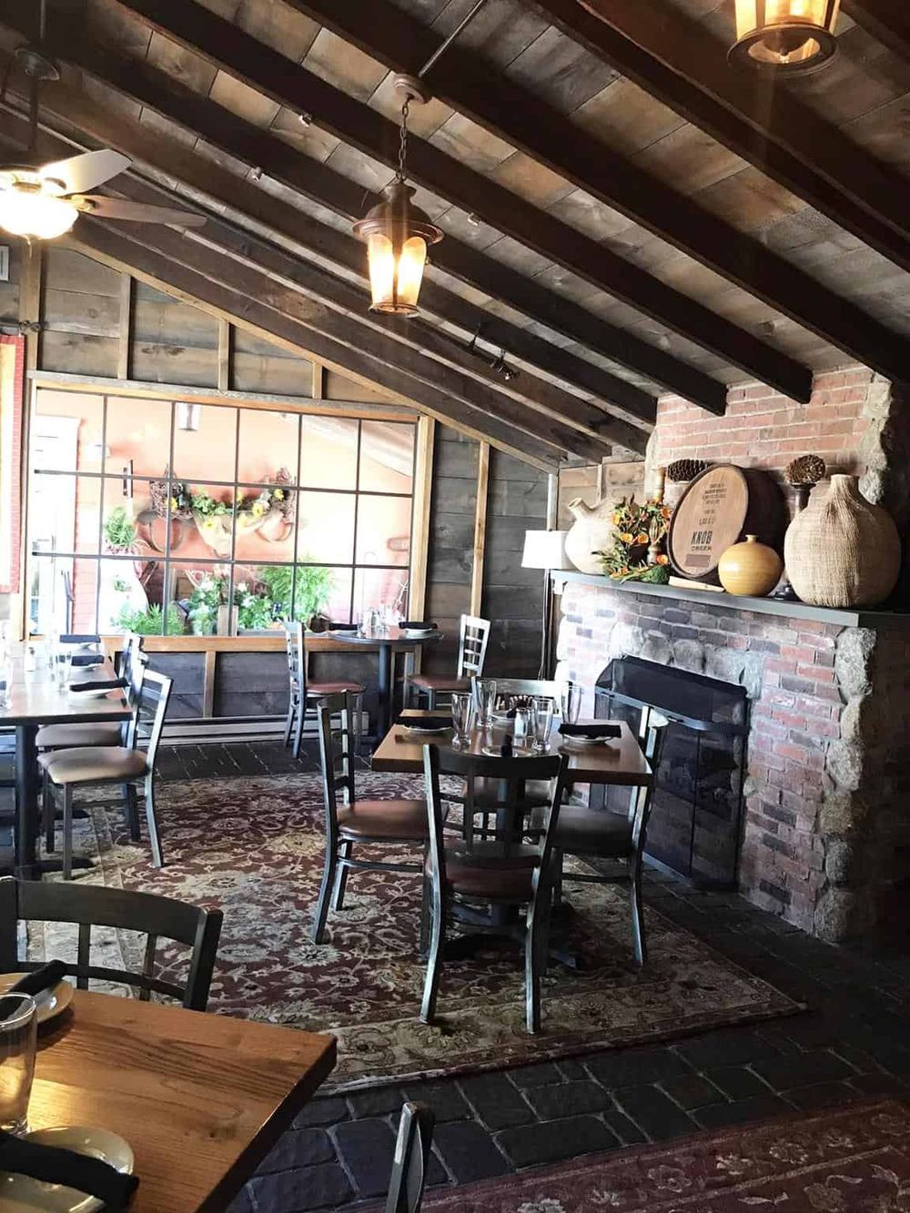 Cozy rustic restaurant interior with wooden beams, brick fireplace, and vintage decor for dining experience.