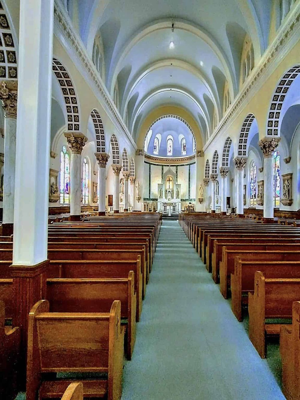 Serene church interior with high vaulted ceilings, stained glass windows, and wooden pews.