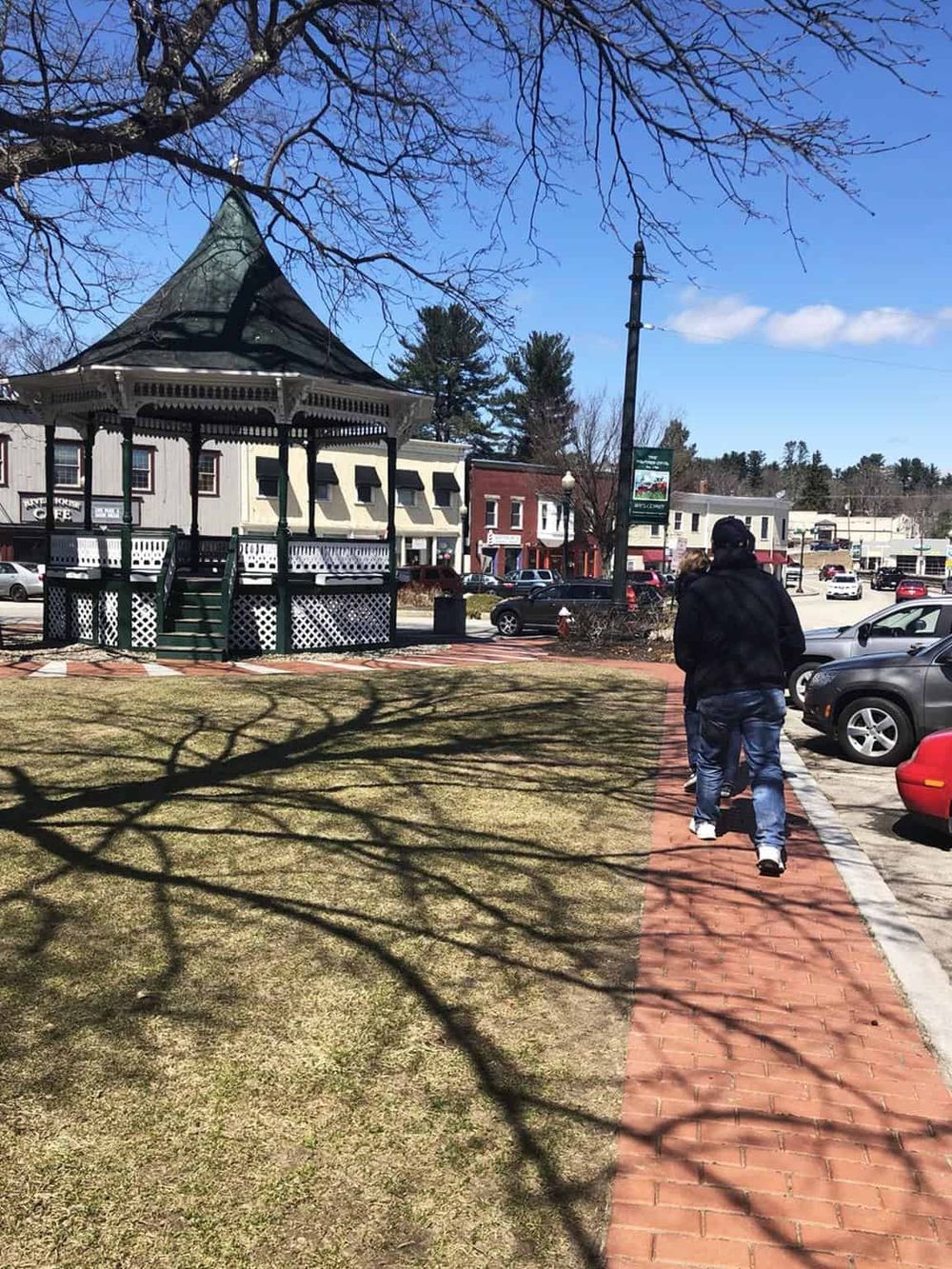 Charming downtown park with gazebo, brick walkway, and nearby shops and parking.