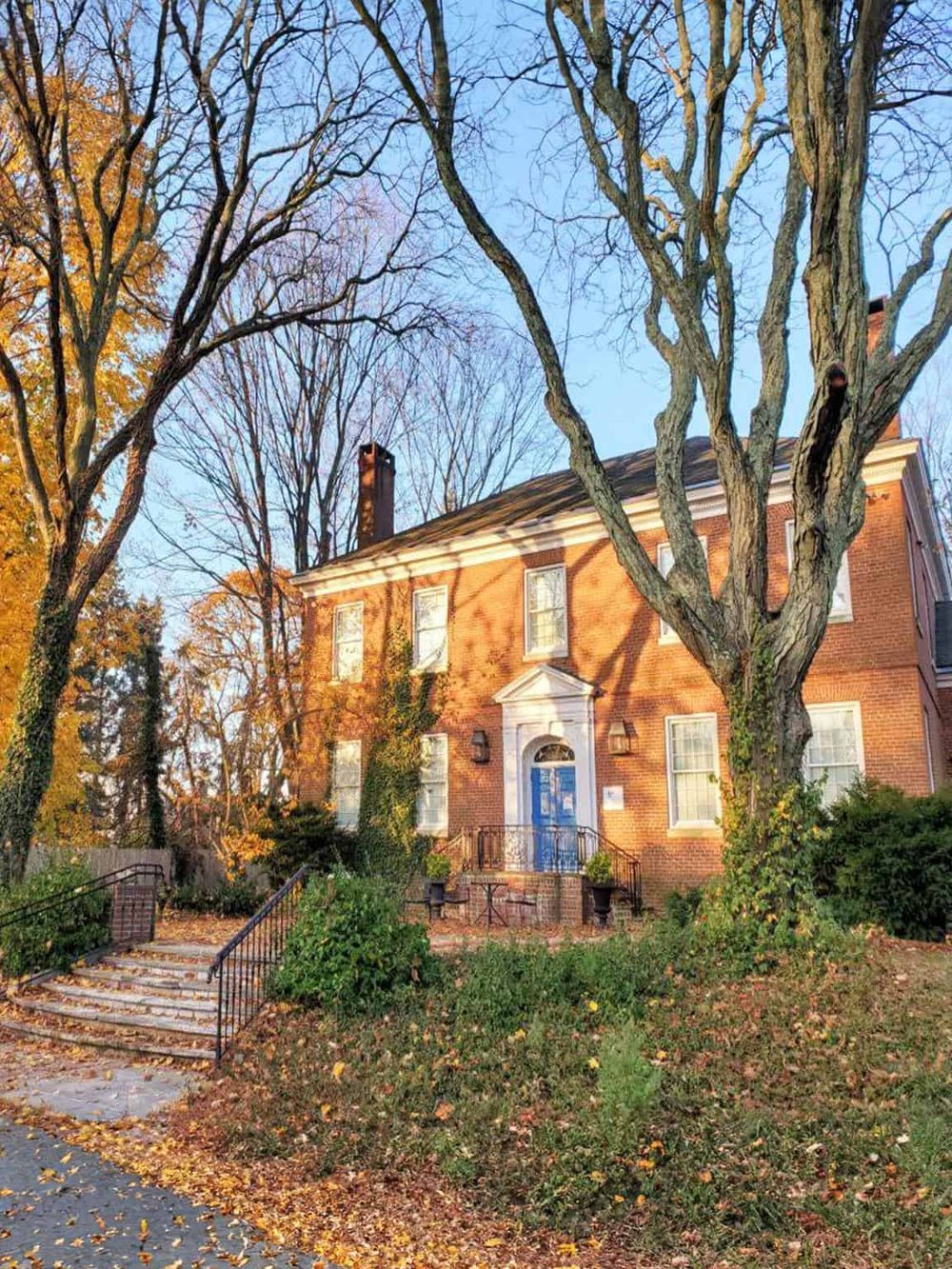 Historic brick house in autumn with leafless trees, perfect for exploring local architecture and history.