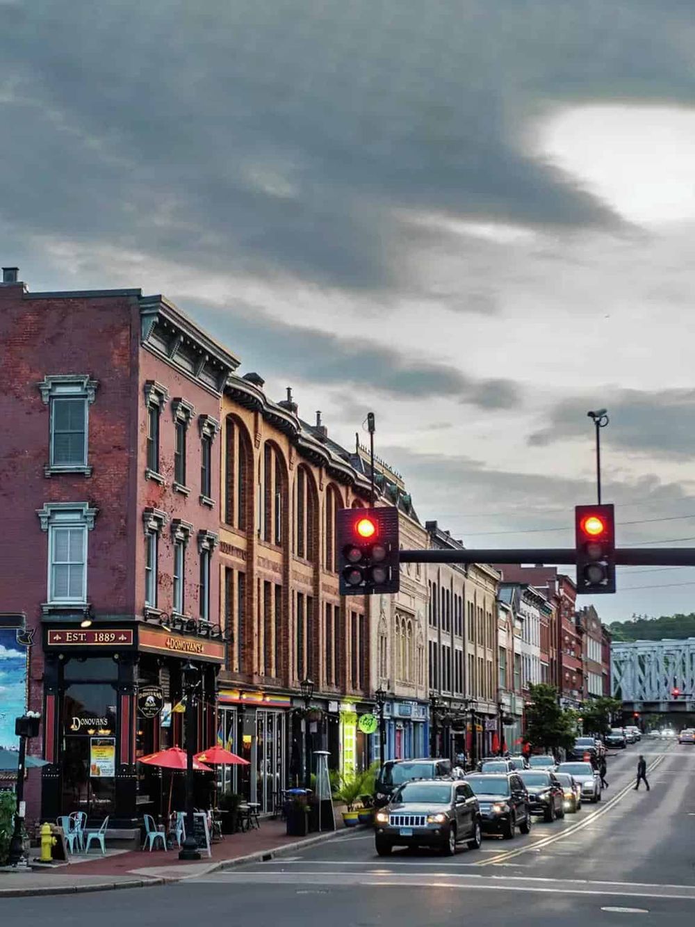 Vintage downtown city street with historic buildings, traffic, and a traffic light in the evening.