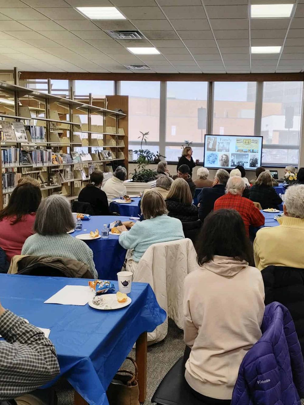 Quiet library event space for storytelling or presentations, surrounded by bookshelves and large windows.