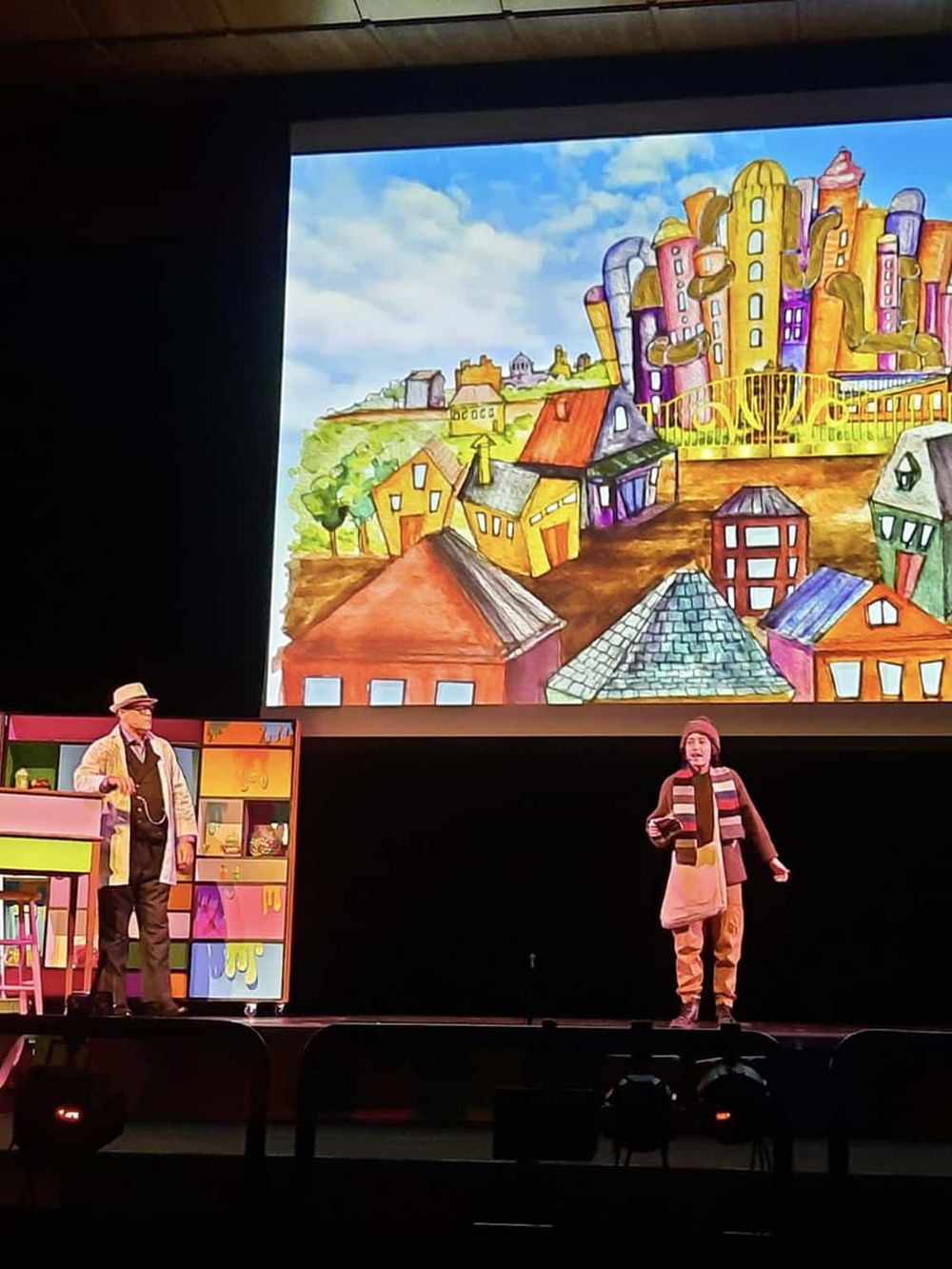 Colorful cityscape illustration displayed on stage for QuestForDirections presentation.