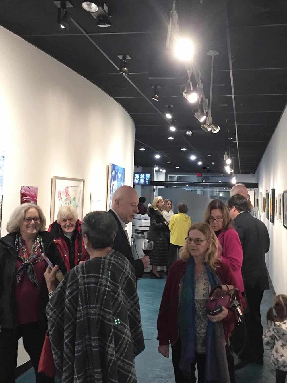 People viewing art at an art gallery during an exhibit opening.