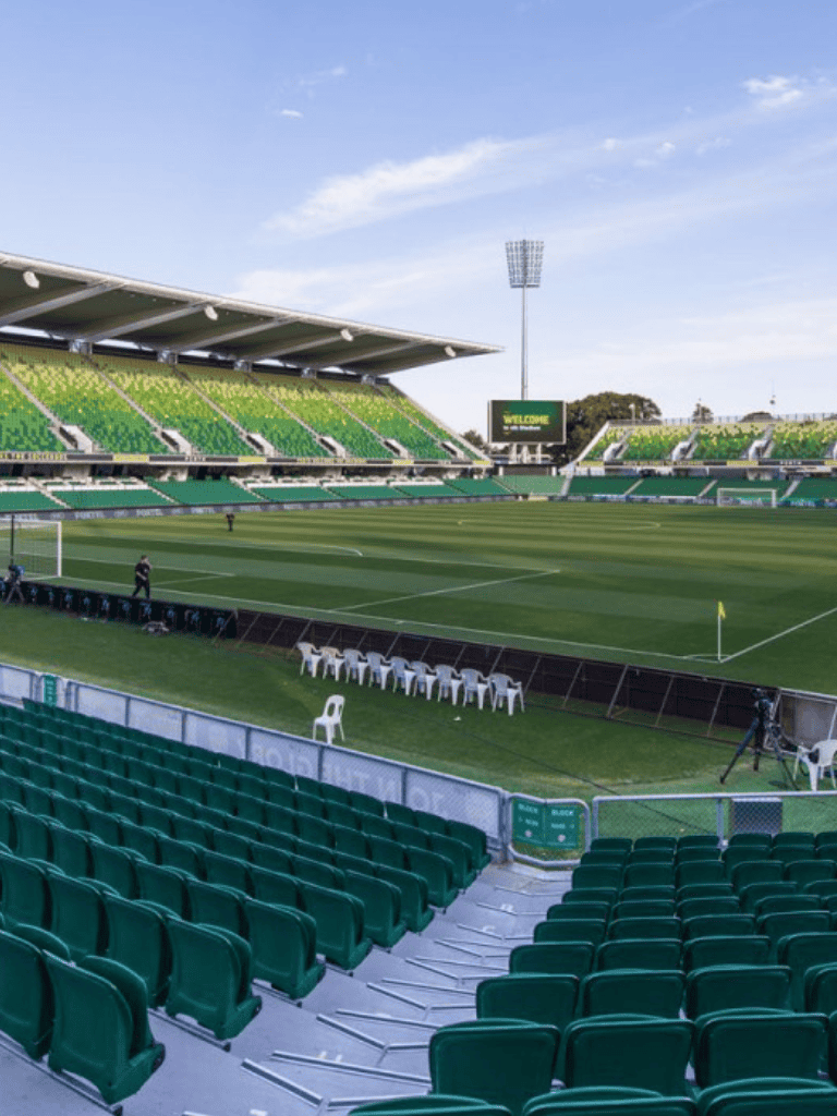 Quiet sports stadium with green seating, field, and sky.