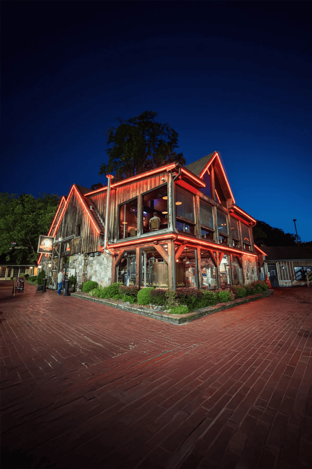 Cozy rustic restaurant at night with neon lighting, outdoor patio, and welcoming ambiance.