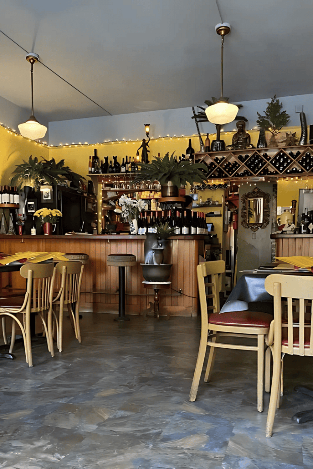 Cozy restaurant interior with wine bottles, plants, and warm lighting, perfect for dining and wine tasting experiences.