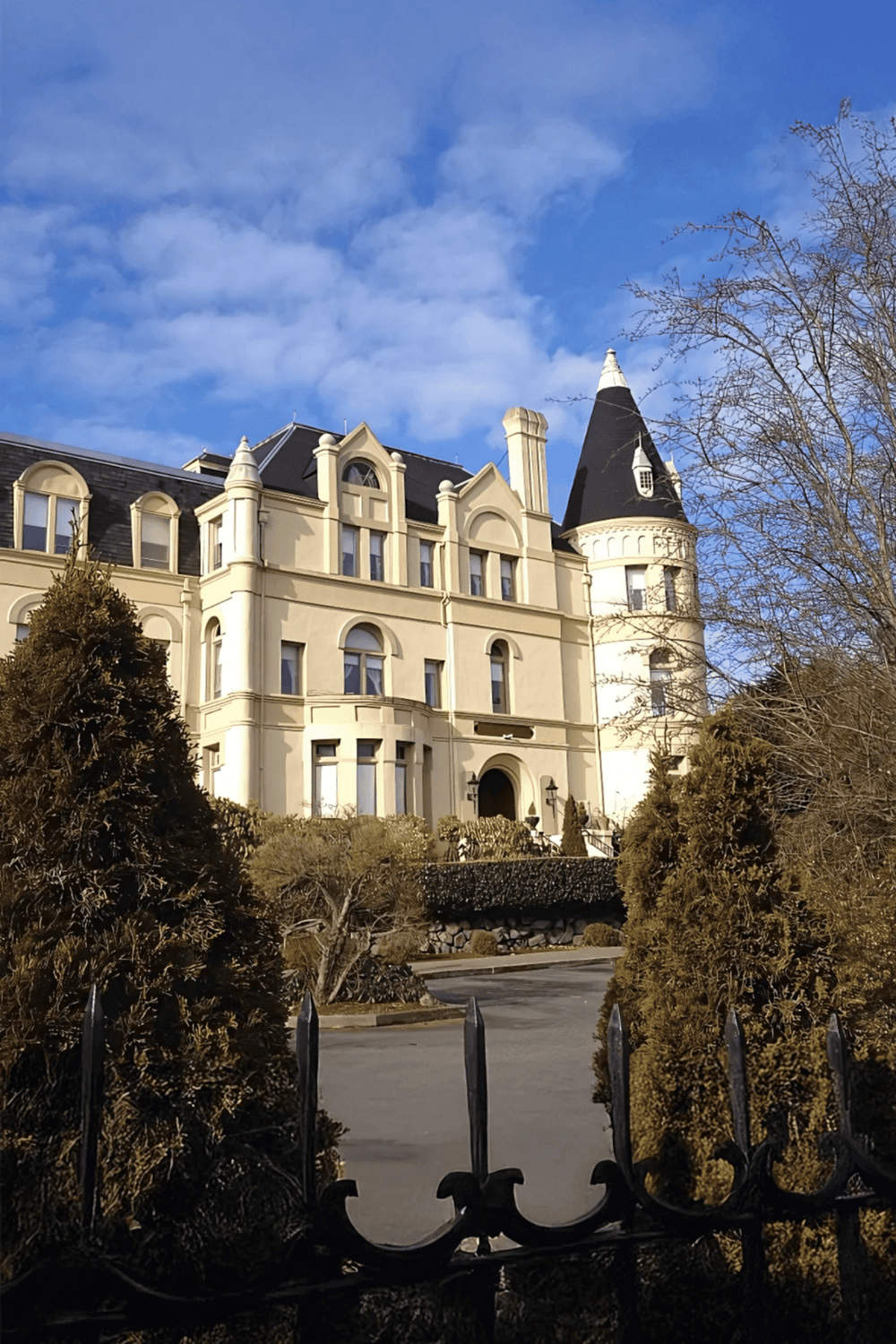 Elegant Victorian-style mansion with turret and lush landscaping at QuestForDirections.