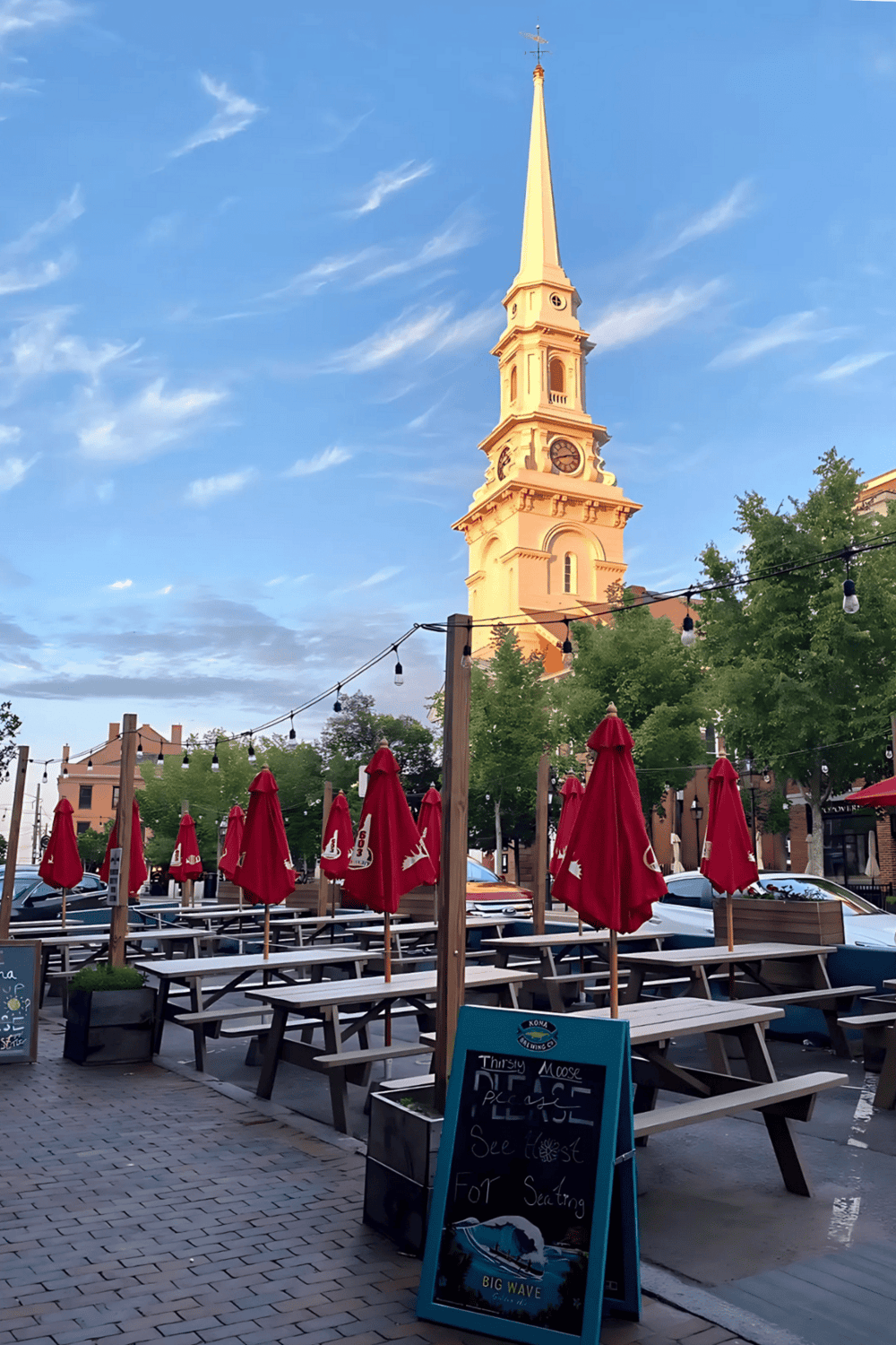 Historic church tower in downtown with outdoor dining on a clear evening.