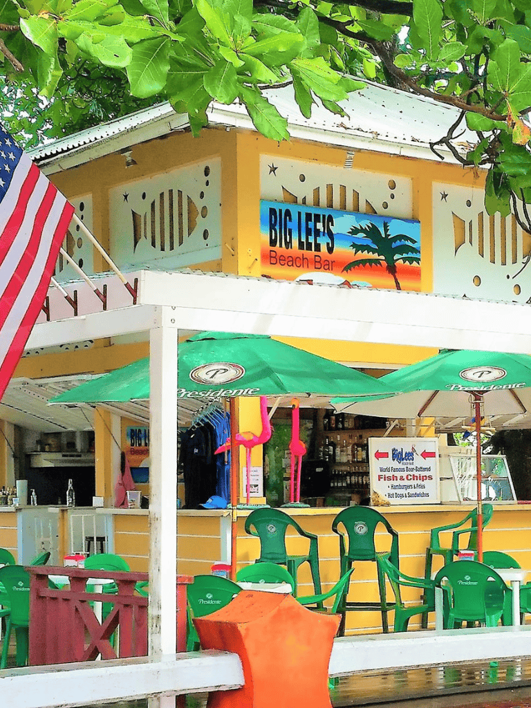 Colorful beach bar with outdoor seating, umbrellas, and tropical decorations at Big Lee's on Quest for Directions.