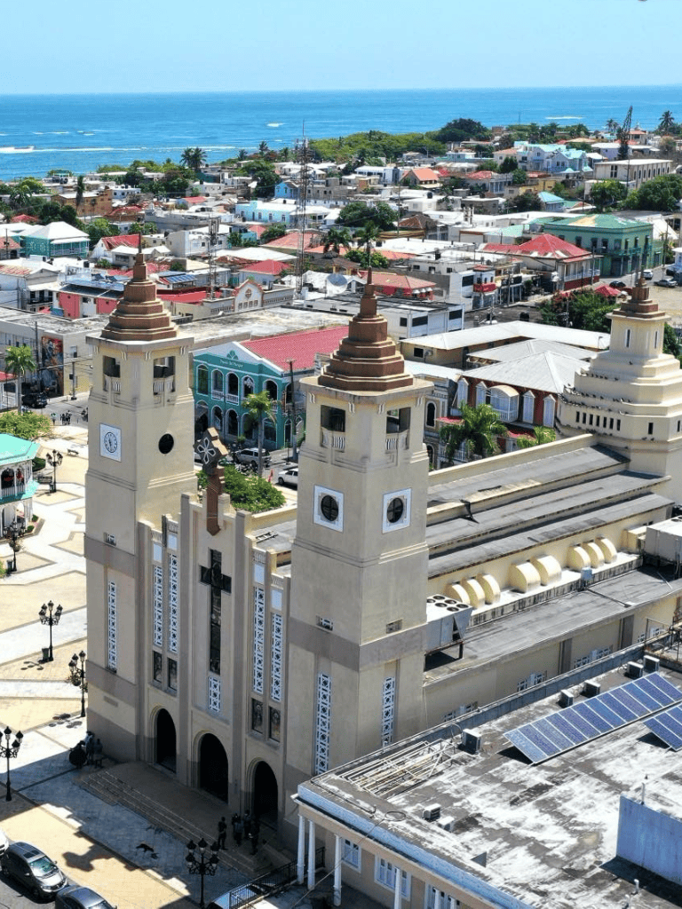 View of a colorful coastal town with a historic church, vibrant buildings, and ocean in the background.