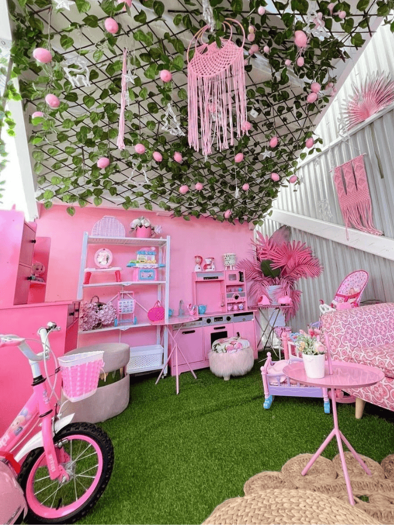 Pink themed indoor playroom with toys, furniture and decorative accents.