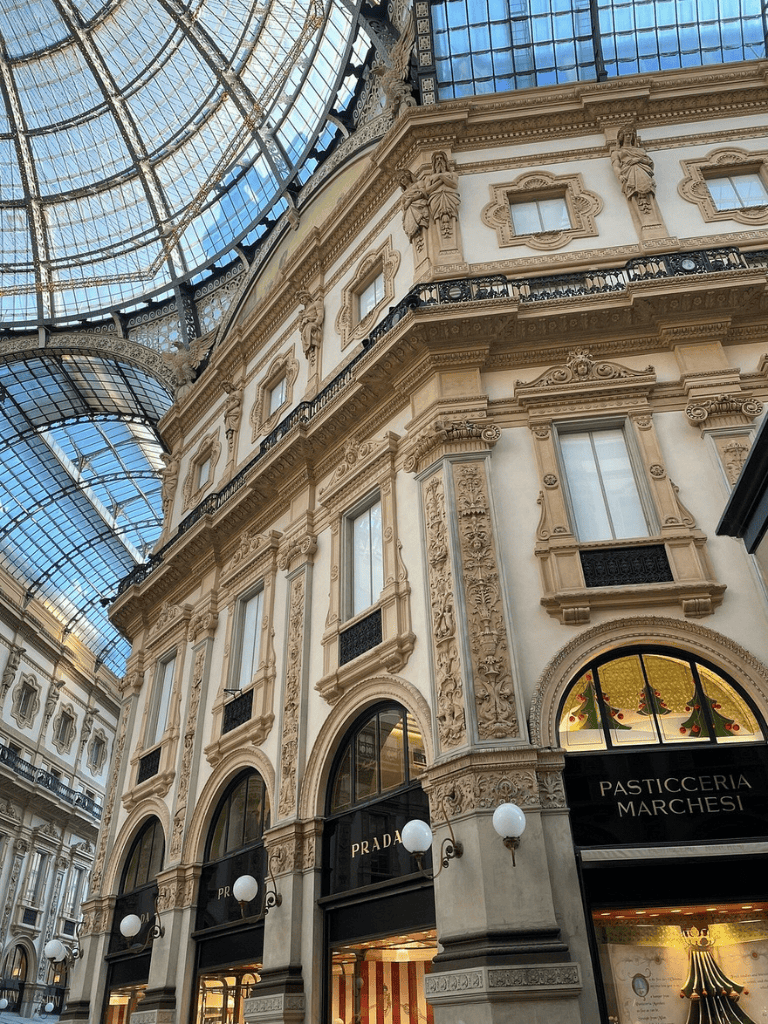 Luxurious shopping arcade with ornate architecture and glass-domed ceiling in Milan, Italy.