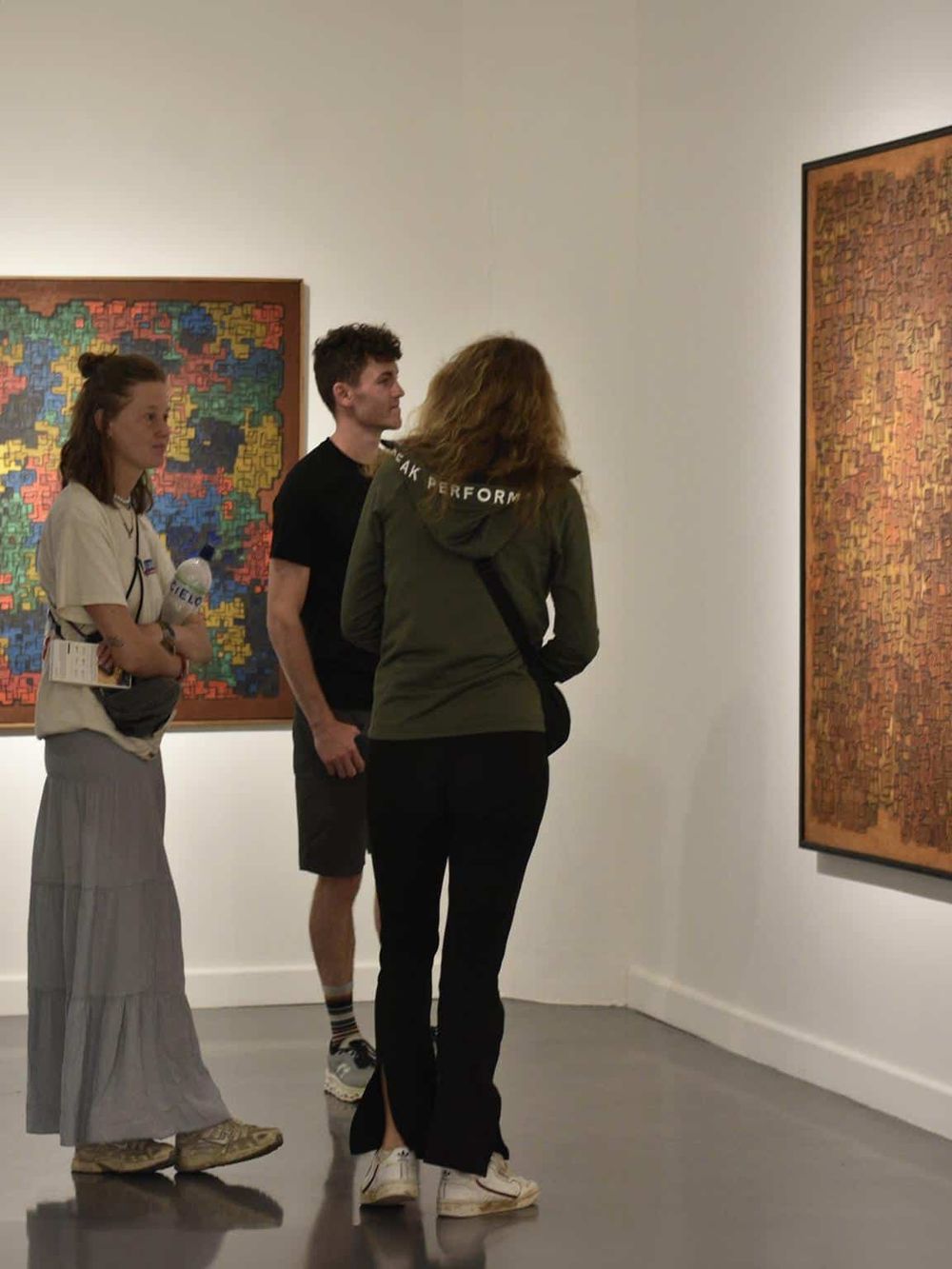 Vibrant abstract art displayed in an art gallery with visitors viewing and discussing the artwork.