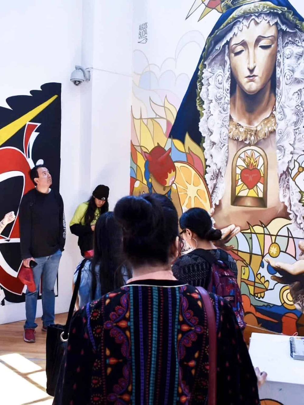 Vibrant religious mural art at Quest For Directions art exhibit with visitors viewing the artwork.