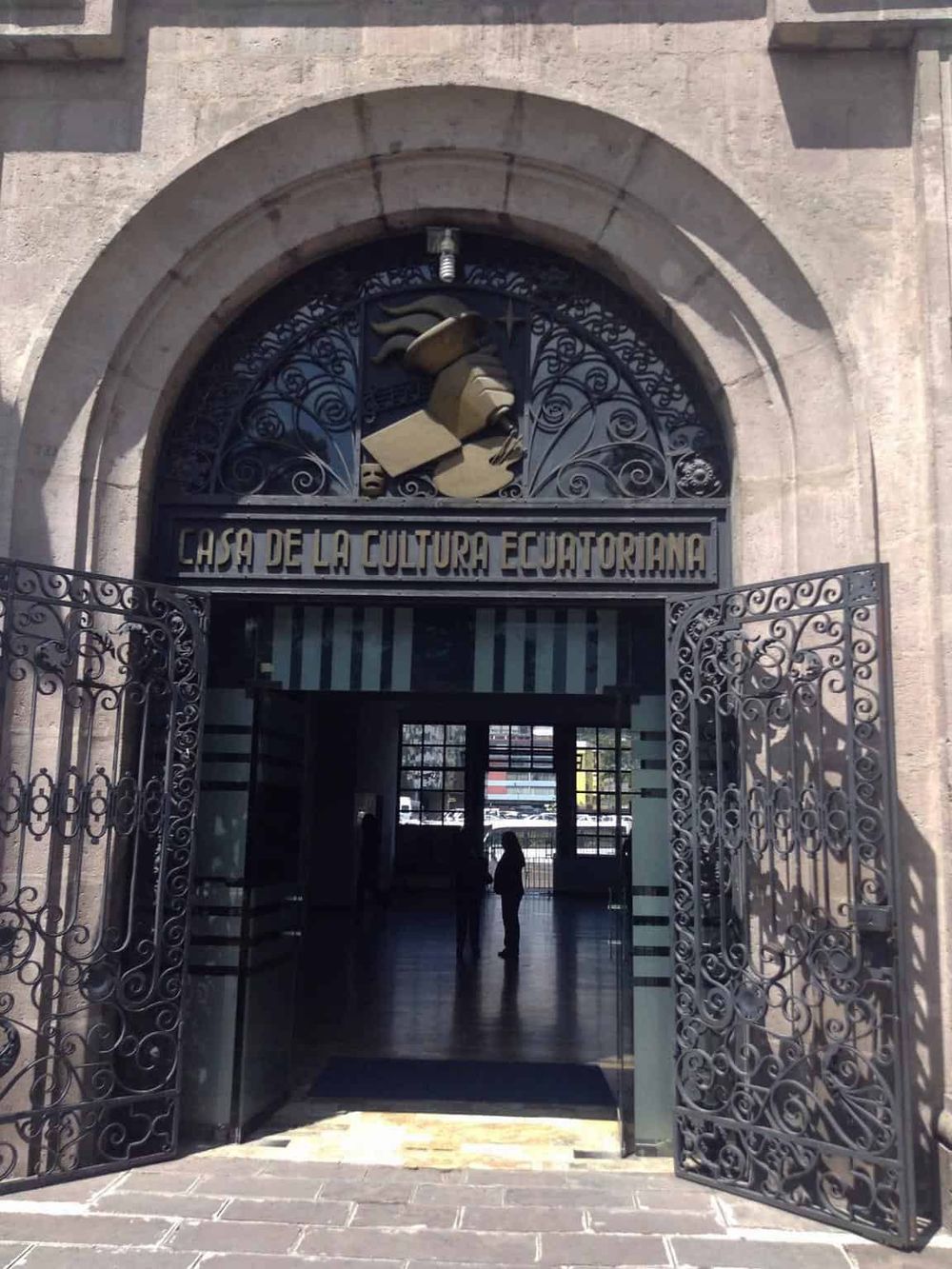 Historian Ecuadorian culture center entrance with ornate gate and sculpture, architectural details, and visitors inside.
