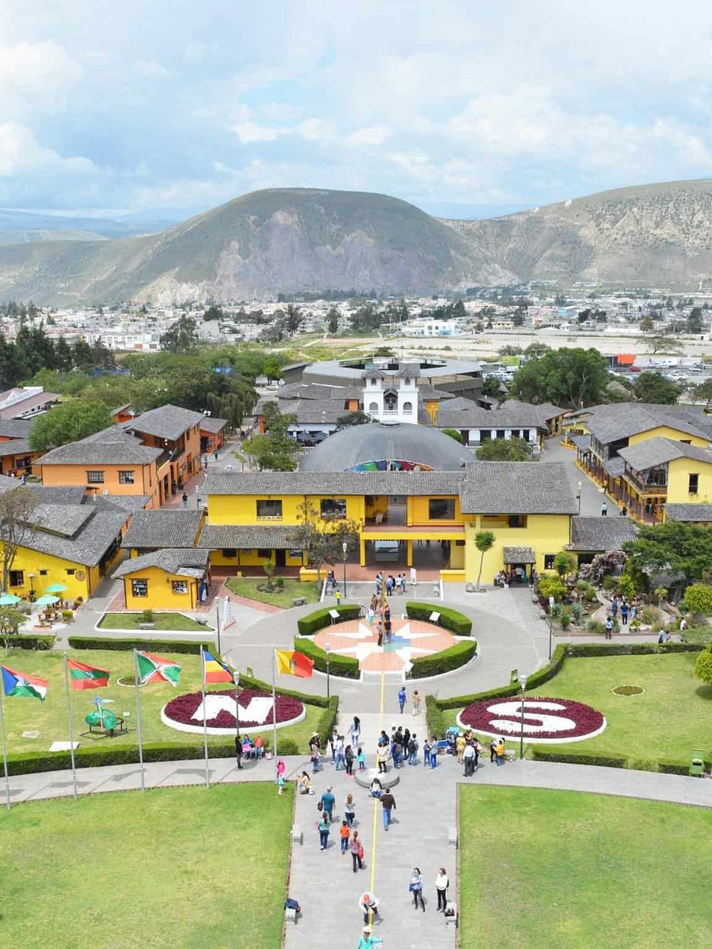 Colorful shopping and dining area in Quest for Directions, with vibrant buildings and scenic mountains in the background.