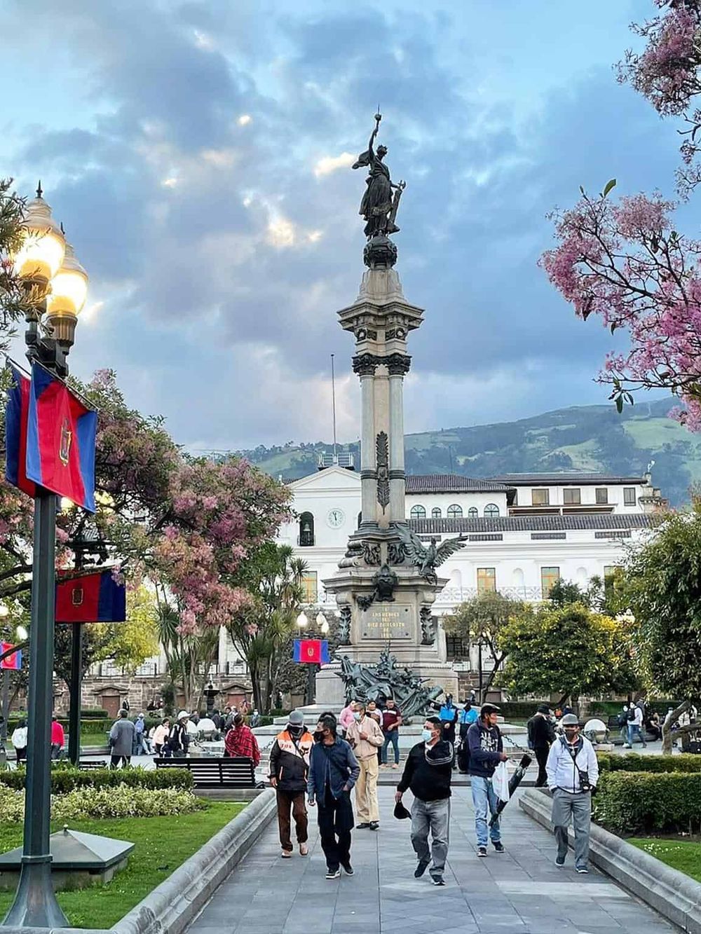 Colorful public square with monument, visitors, and scenic background in Quito, Ecuador.