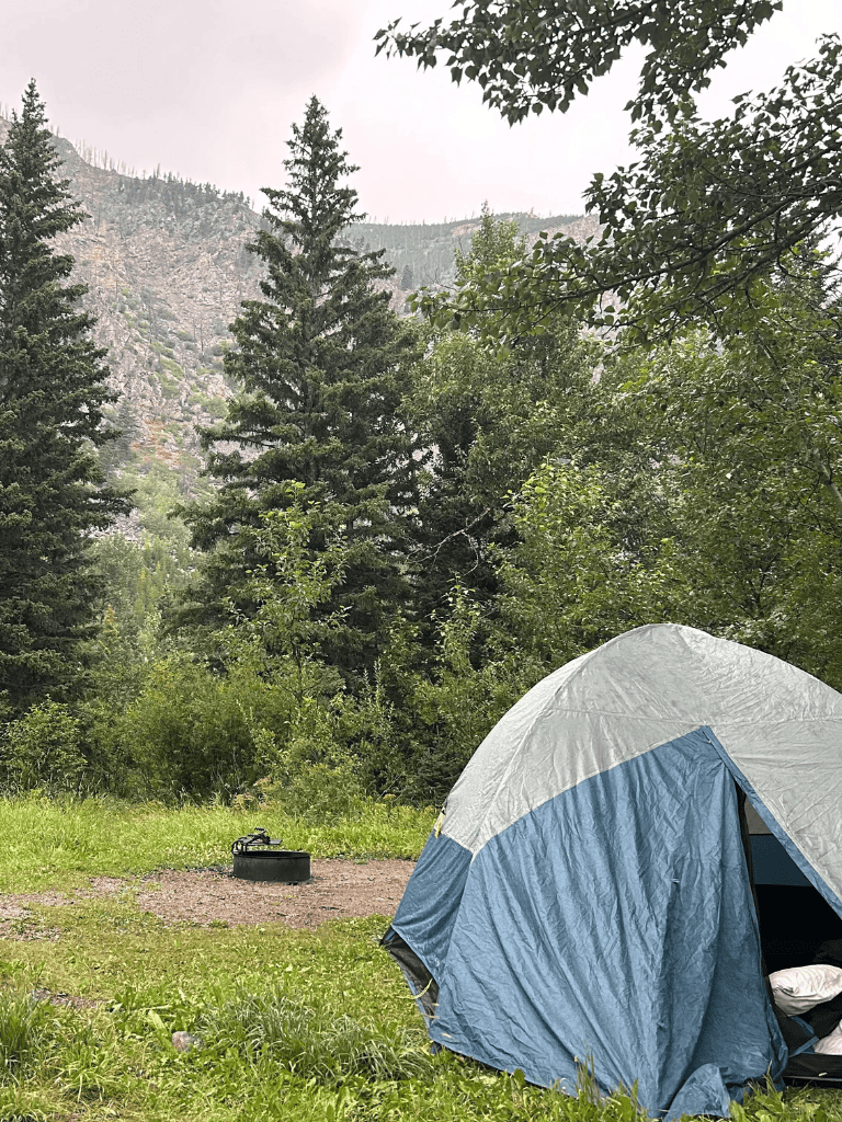 Quiet camping spot surrounded by lush trees and mountain views, perfect for outdoor adventures.