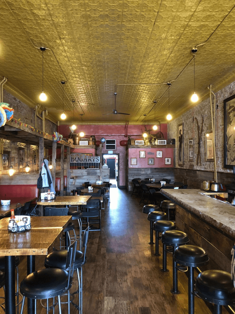 Cozy rustic restaurant interior, warm lighting, wooden furniture, eclectic decor, inviting dining space.