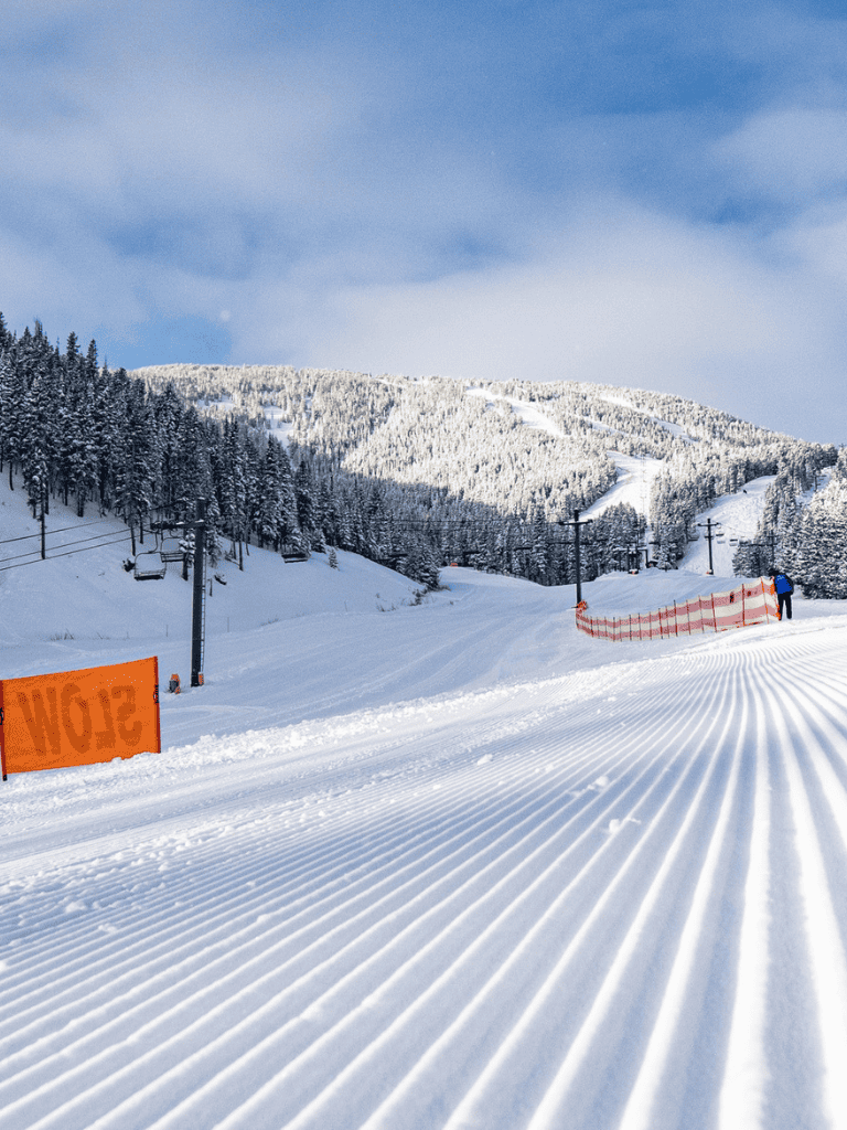 Fresh powder snow at ski resort with clear blue sky and ski lift infrastructure.