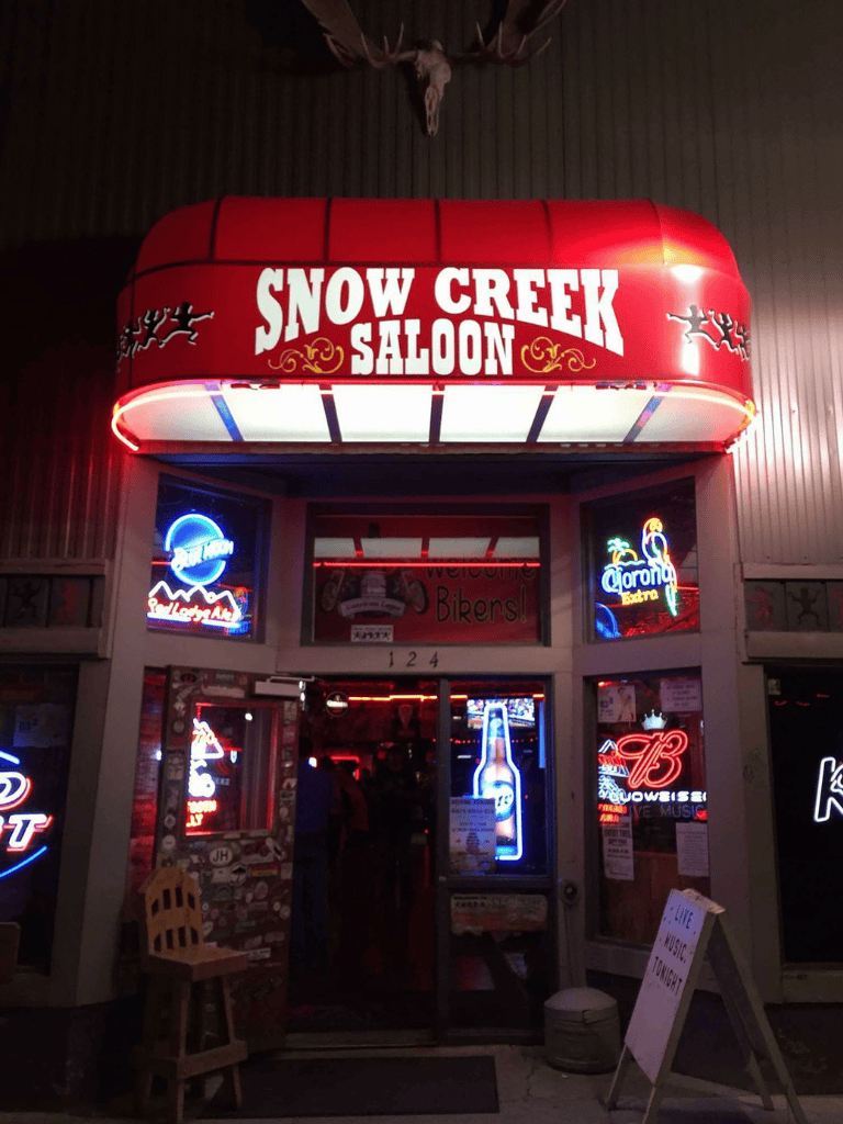 Snow Creek Saloon entrance with neon signs and welcoming atmosphere.