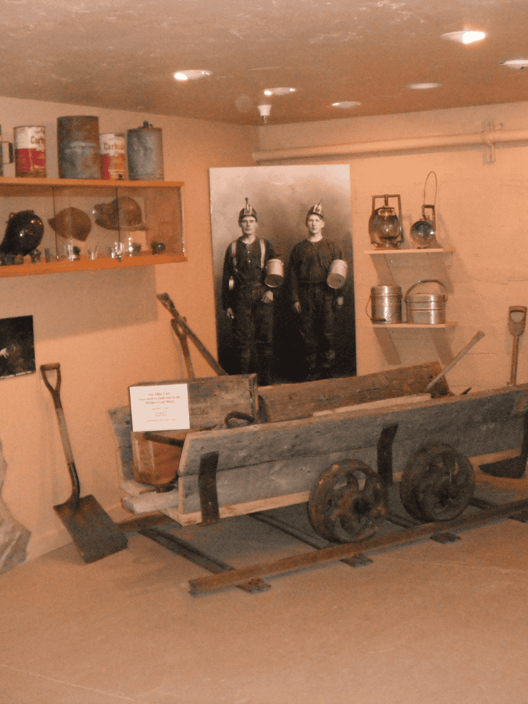 Explosive history museum display with vintage tools and photographs related to military or wartime efforts.