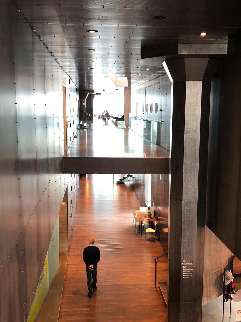 Modern architectural interior with sleek black and gray walls, wooden floors, and natural light.