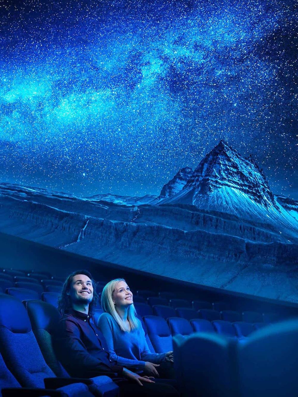 Stargazing at QuestForDirections immersive cinema with mountain and galaxy backdrop in theater setting.