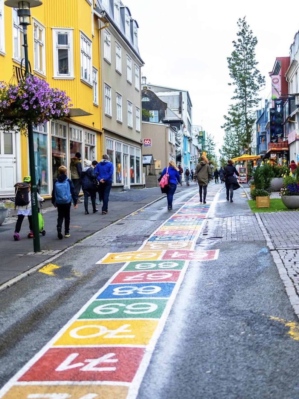 Colorful hopscotch game on city street in Reykjavik, Iceland, with pedestrians, shops, and vibrant buildings.