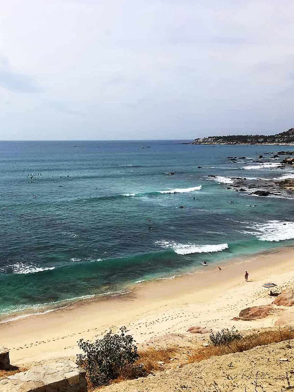 Beach surfing and coastal scenery with people enjoying the ocean waves and sandy shore.