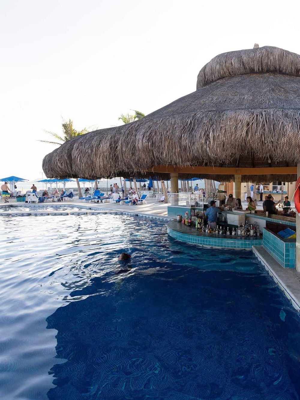Luxurious poolside bar at a tropical resort with thatched roof and ocean views for relaxing vacations.