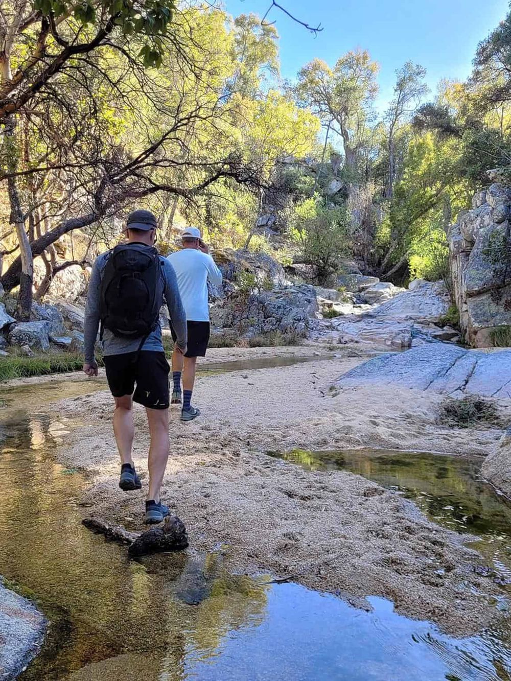 Hiking in a scenic mountain creek landscape with two explorers enjoying nature.