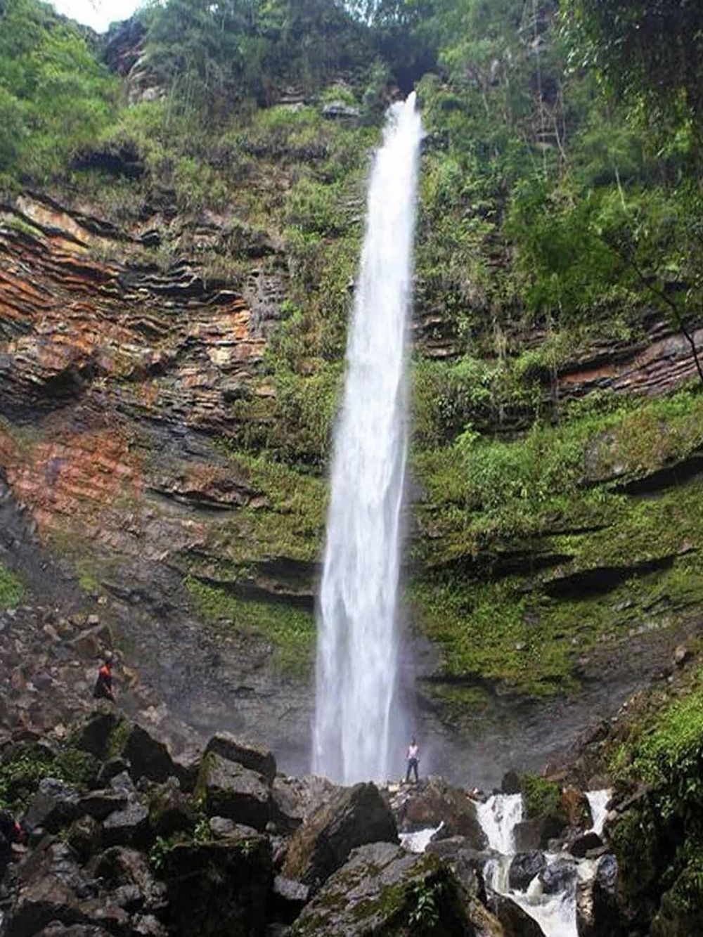 Vibrant waterfall cascading down lush green cliffs in a scenic natural landscape.