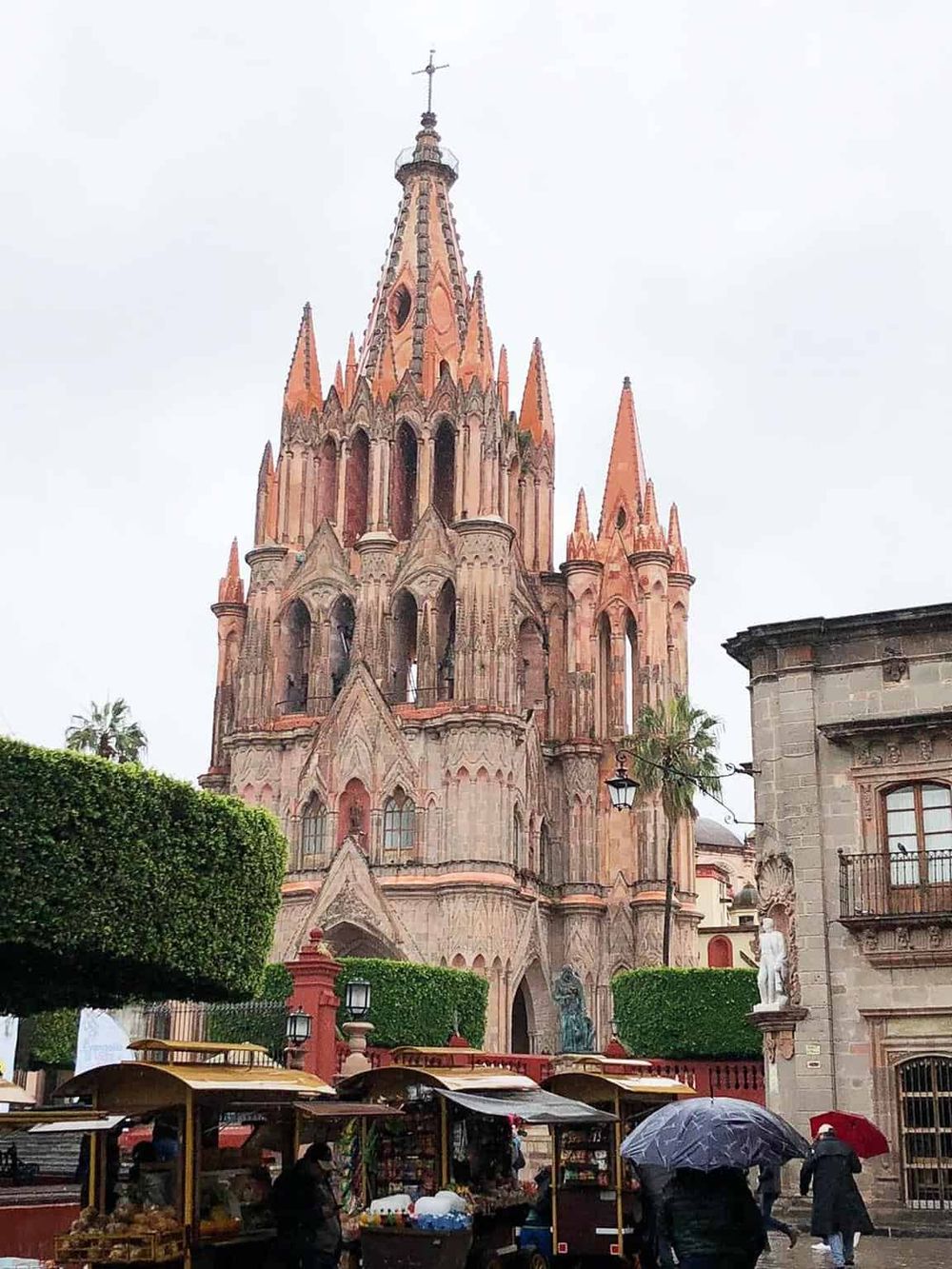Colorful Gothic cathedral in Mexico City with street vendors and umbrellas in foreground.