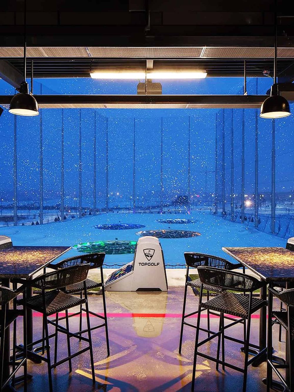 Indoor golf simulator with city view in a modern entertainment venue.