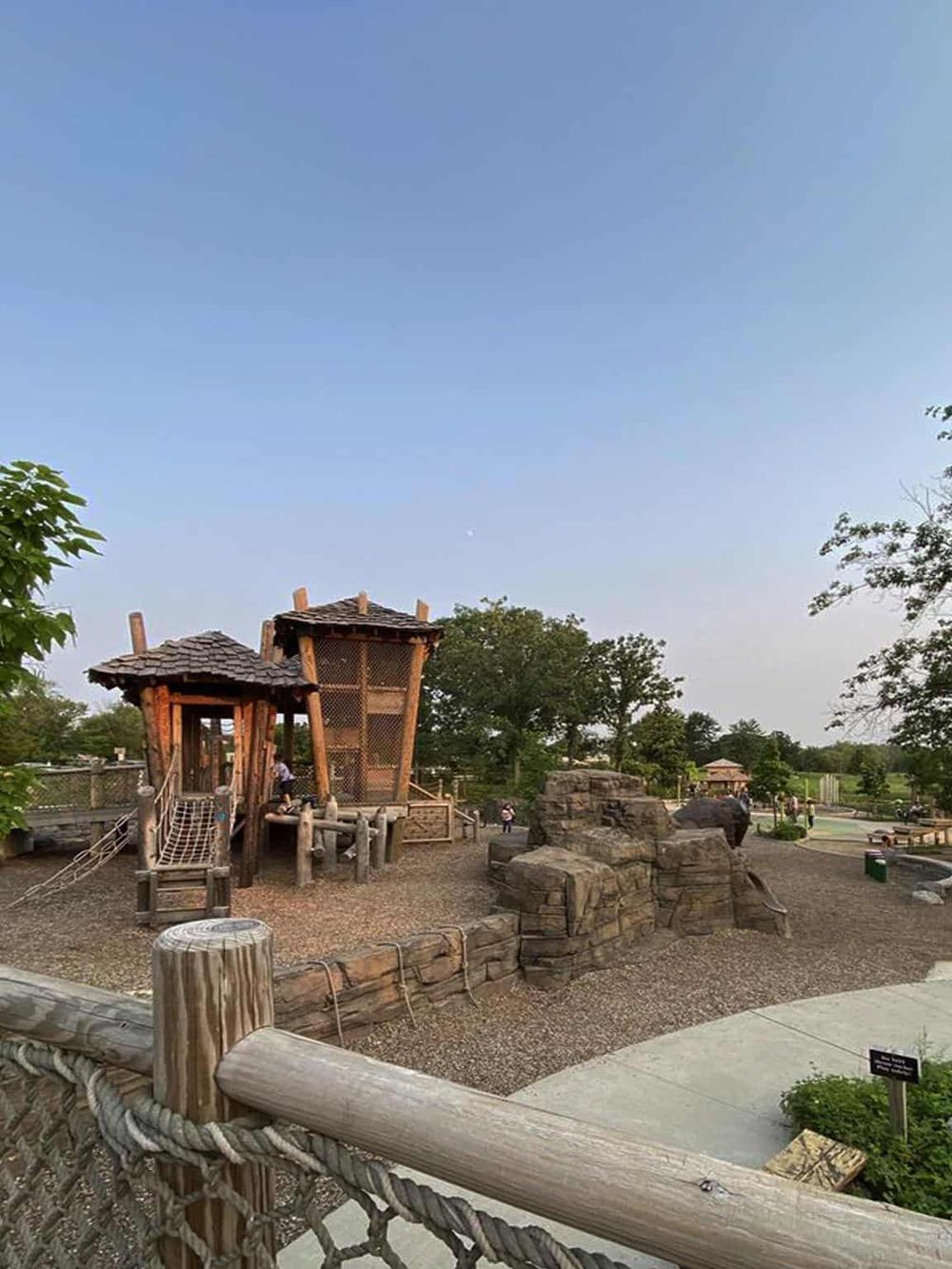 Playground with wooden structures and rocks in a park during daytime.