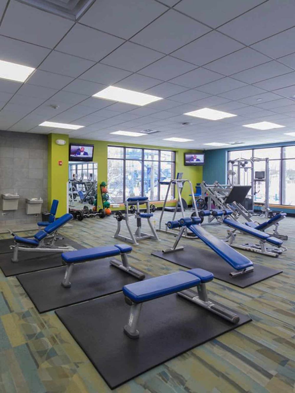 Modern gym fitness center with workout equipment and exercise benches for physical training.