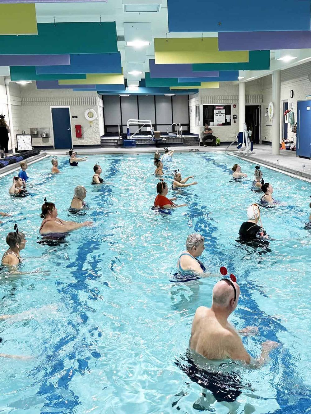 Aqua fitness class at indoor swimming pool for health and wellness.