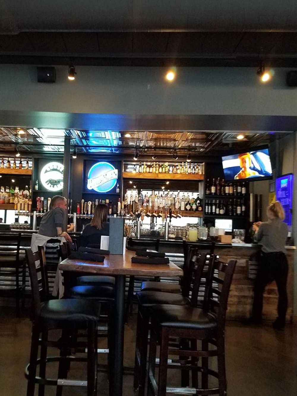 Cozy bar interior with beer taps, neon signs, and TVs at QuestForDirections.