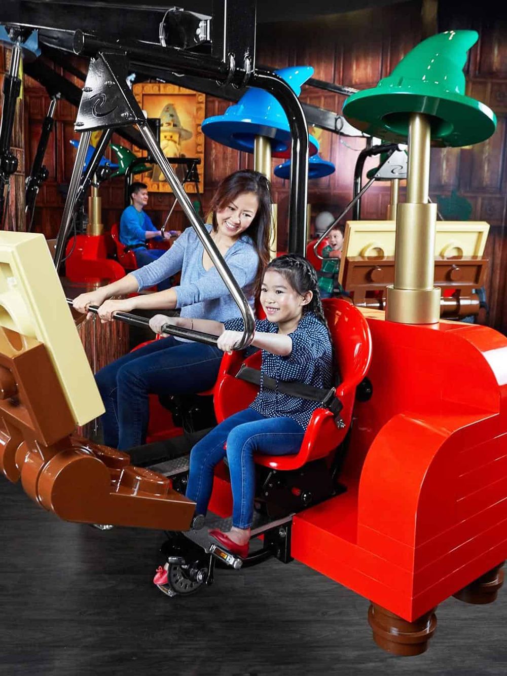 Riding a colorful indoor amusement park ride with children and a mother, fun family entertainment at Quest for Directions.
