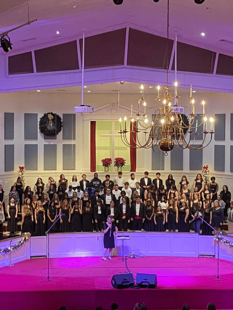 Elegant choir performance in a spacious church with holiday decorations and a grand chandelier.