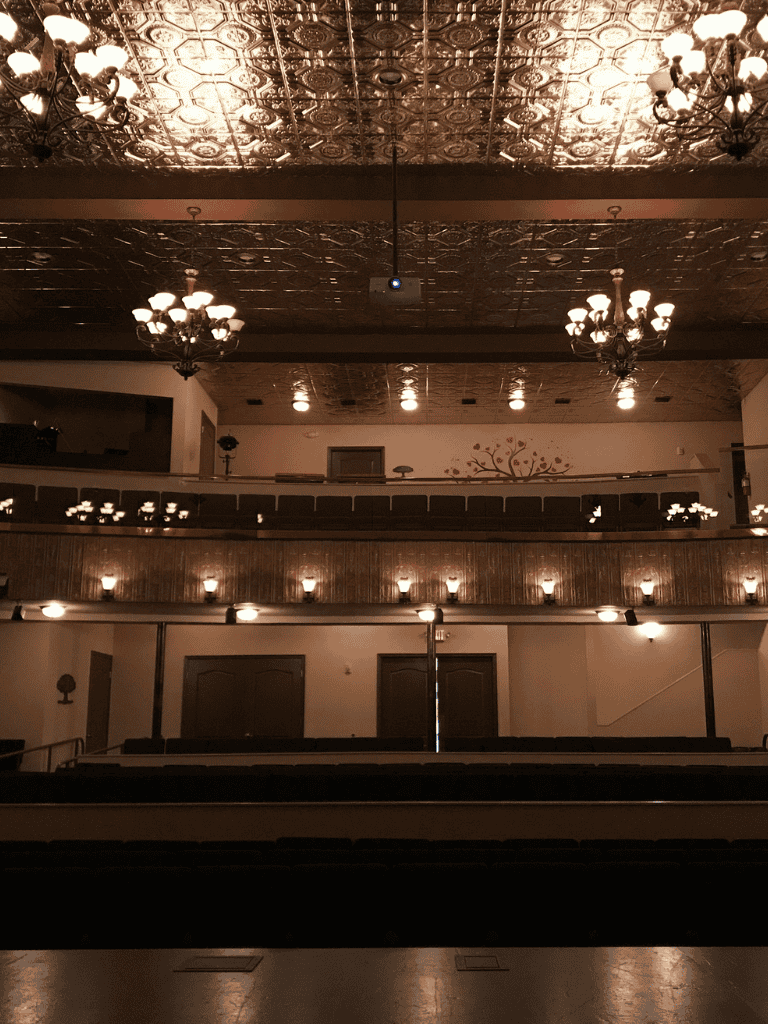 Ornate historic theater interior with vintage chandeliers and decorative ceiling lighting.