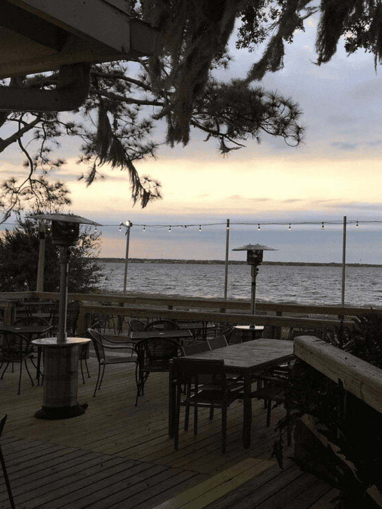 Relaxing lakeside outdoor dining with string lights and heaters, ideal for lakeside dining experience.